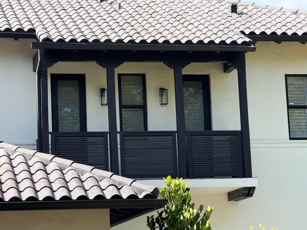 Covered second-floor balcony with wood trim on a Mediterranean-style home on Madeira Ave, Coral Gables

